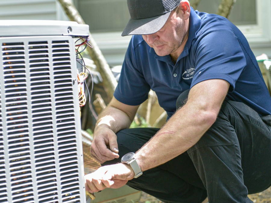 A Sam's Air Control technician servicing an outdoor central A/C condenser